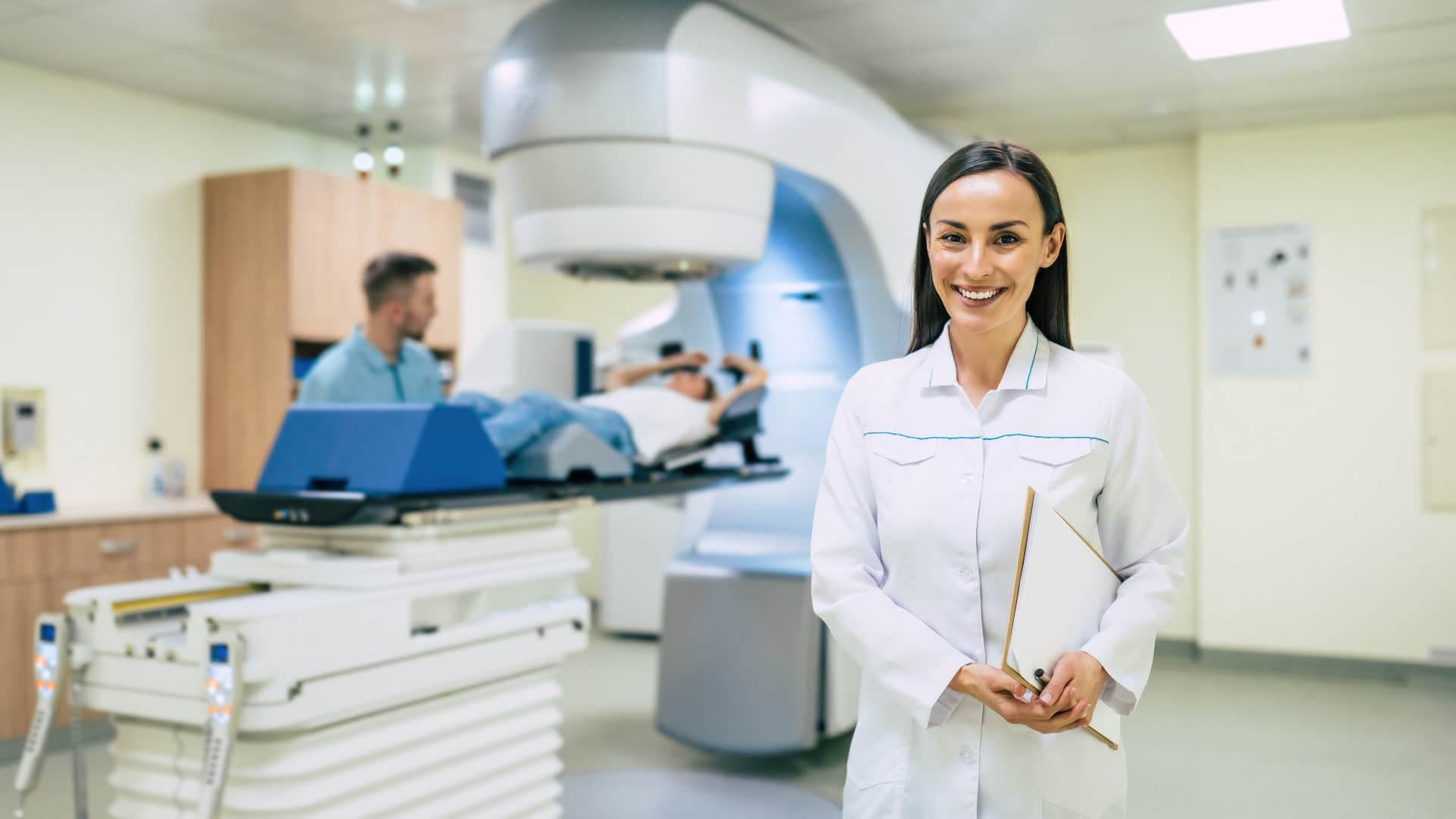 radiation therapist and colleague working with client in machine